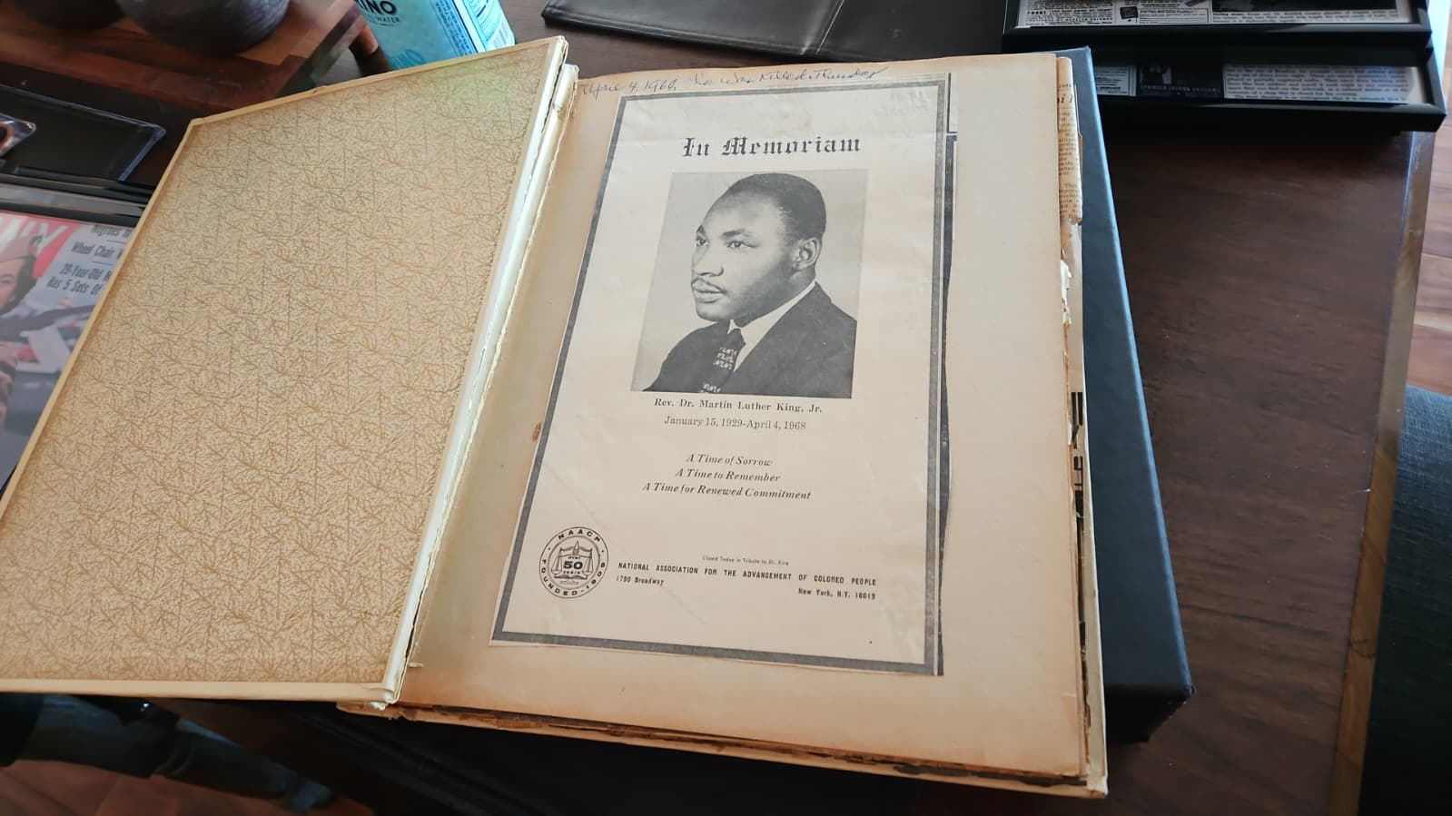 A scrapbook opened to an NAACP In Memoriam page for Dr. Martin Luther King Jr., with a handwritten annotation at the top reading 'April 4, 1968. He was killed Thursday.'